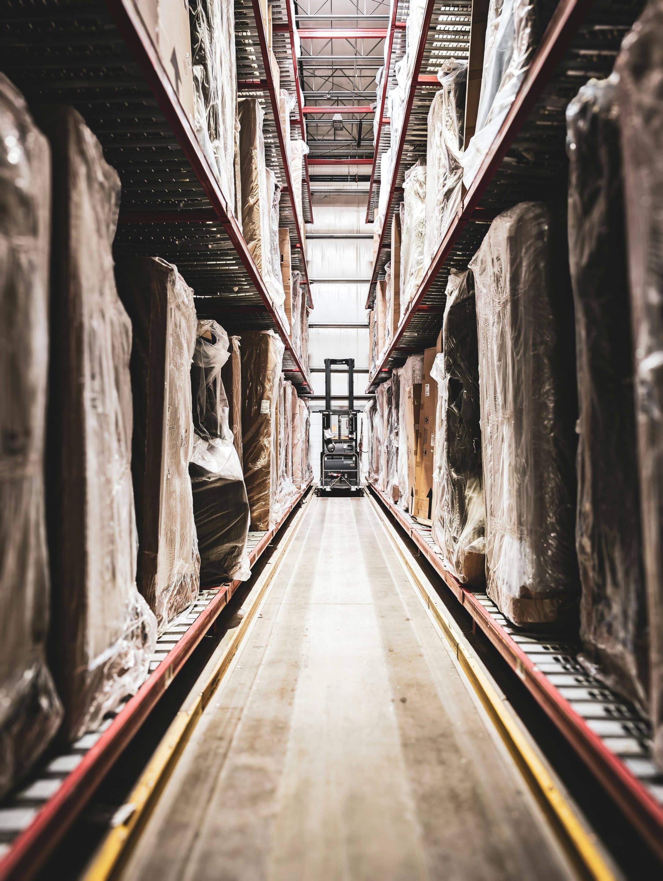 Warehouse aisle with goods and forklift.